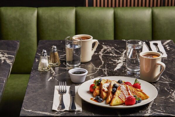 A dining table with a plate of food, a cup of coffee, and a glass of water.