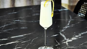 Een hoog glas met een citroenzeste op een marmeren tafel.