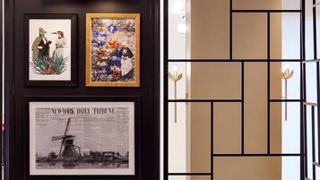 A wall with framed artwork, including a newspaper clipping and two framed illustrations.