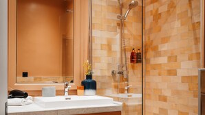 Ein modernes Badezimmer mit einer gläsernen Duschkabine, einem großen Spiegel und einem weißen Waschbecken.