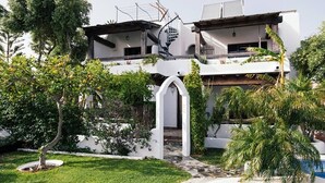 A two-story building with a white exterior, a spiral staircase, and a pool area.