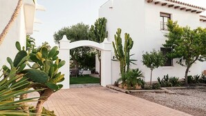 A courtyard with a white building, a cactus garden, and a paved walkway.