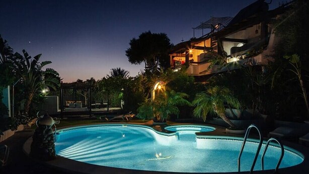 A swimming pool at dusk with a modern house in the background.