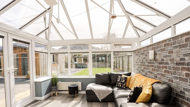 Lasiveranta, jossa on musta nahkasohva, patteri ja näkymä puutarhaan.