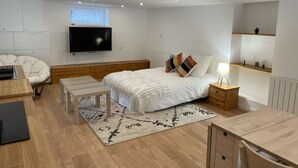 Et moderne soveværelse med seng, natbord, lampe og et fjernsyn monteret på væggen.