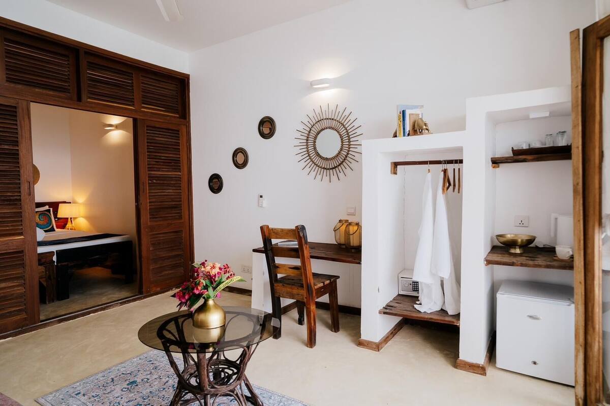 Un espacio habitable compacto con comedor, una pequeña cocina y un armario con espejo.