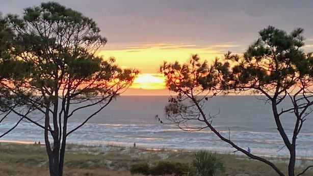 A sunset view with trees framing the scene. - Oceanfront Sunrises in Upgraded Seaside Villa 225 (Hilton Head Island)
