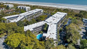 A coastal hotel with multiple buildings, a parking lot, and a beach in the background. - Oceanfront Sunrises in Upgraded Seaside Villa 225 (Hilton Head Island)