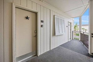 A covered walkway with a door, a mailbox, and a window with shutters. - Oceanfront Sunrises in Upgraded Seaside Villa 225 (Hilton Head Island)