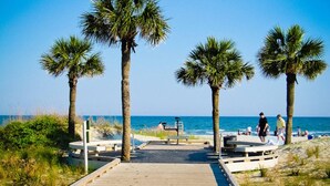 A beach pathway with palm trees, a wooden boardwalk, and a bench. - Oceanfront Sunrises in Upgraded Seaside Villa 225 (Hilton Head Island)