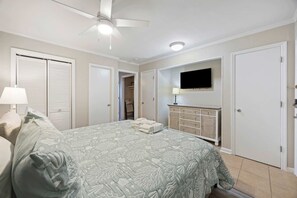A bedroom with a bed, a ceiling fan, a TV, a dresser, and a closet. - Oceanfront Sunrises in Upgraded Seaside Villa 225 (Hilton Head Island)