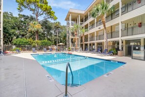 A swimming pool with lounge chairs and a multi-story building with balconies. - Oceanfront Sunrises in Upgraded Seaside Villa 225 (Hilton Head Island)