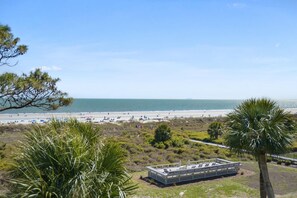 A beach view with a clear sky, a sandy beach, and a few people. - Oceanfront Sunrises in Upgraded Seaside Villa 225 (Hilton Head Island)