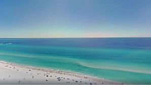Une plage aux eaux turquoise et limpides, bordée d’un rivage sablonneux.