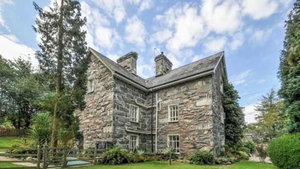 A stone house with a large garden and a wooden fence. - Cae Nest Hall (llanbedr)