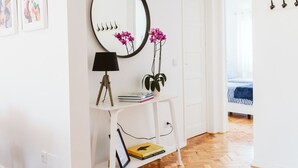A white room with a mirror, a lamp, a plant, and a bed with striped bedding. - NEW! Belém Riverside 2 bedrooms completely renovated (Lisboa)