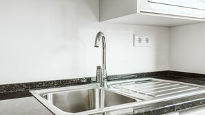 A modern kitchen with a stainless steel sink, a black granite countertop, and white cabinetry. - NEW! Belém Riverside 2 bedrooms completely renovated (Lisboa)
