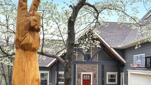 Une maison d’habitation avec une allée, un panier de basketball et une grande sculpture en bois.