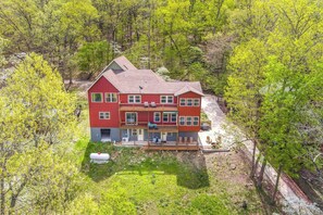 Ein rotes, zweistöckiges Haus mit Balkon, umgeben von Bäumen und einem kleinen Garten.