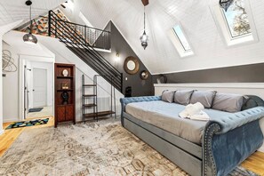 Ein geräumiges Schlafzimmer im Loft-Stil mit einem großen Bett, einer Wendeltreppe und einem Oberlicht.