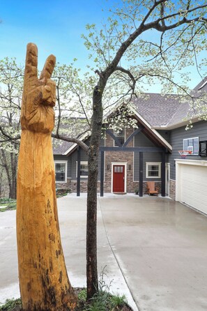 Ein Wohnhaus mit Auffahrt, einem Basketballkorb und einer großen Holzskulptur.