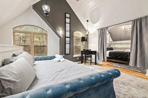 Ein Schlafzimmer mit einem großen Bett, einem Schreibtisch und Blick ins Freie.