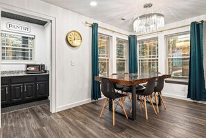 Eine moderne Küche mit dunklem Holzboden, einem Glastisch mit vier Stühlen und einer Pendelleuchte.
