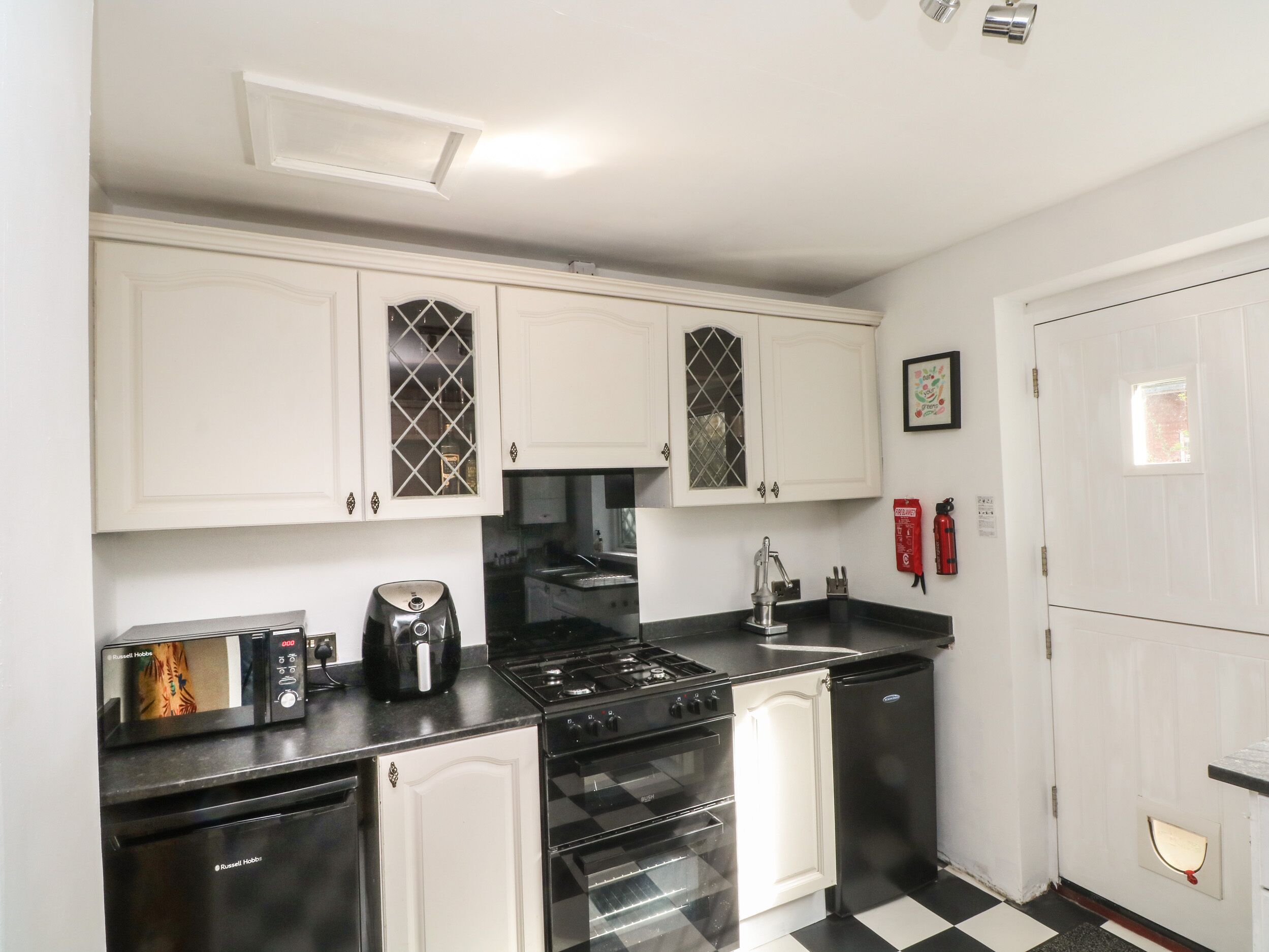 A compact kitchen with white cabinets, a black stove, and a refrigerator.