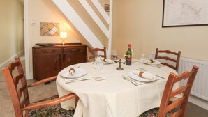 A dining room with a round table set for four, a wooden cabinet, and a lamp. - Magdala (Buxton)