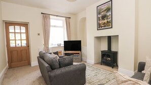 A living room with a sofa, a flat-screen TV, a fireplace, and a poster on the wall. - Magdala (Buxton)