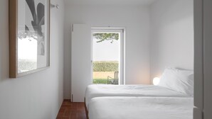 Un dormitorio con dos camas, una puerta que da a un balcón y un cuadro en la pared.
