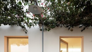 Una casa moderna con un amplio ventanal corredera que da a un dormitorio con cama y un baño pequeño.