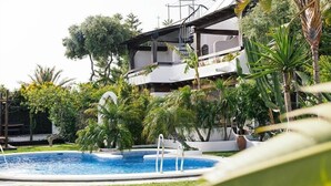 Ein Pool, umgeben von üppigem Grün und einem mehrstöckigen Gebäude mit Balkonen.