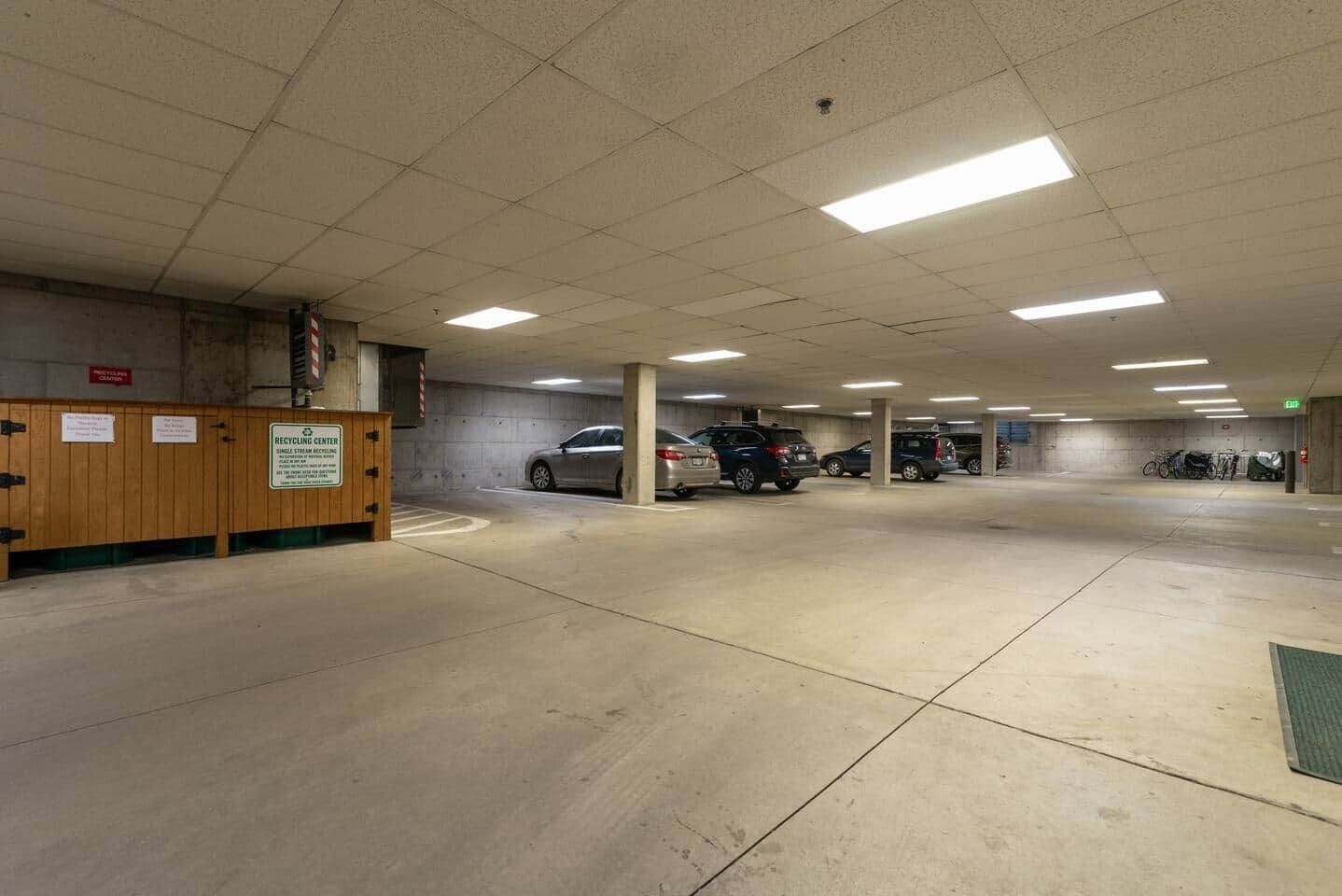A parking garage with multiple levels, concrete floors, and overhead fluorescent lighting.