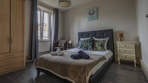 Ein Schlafzimmer mit Bett, Nachttisch, Stuhl, Kleiderschrank und einem Fenster mit Vorhängen.