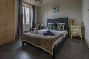 A bedroom with a bed, a nightstand, a chair, a wardrobe, and a window with curtains. - i-love-colmar - Les Remparts - Parking (Colmar)