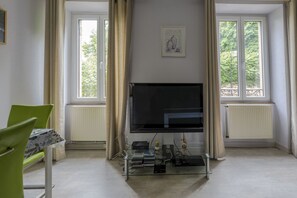 Una sala de estar con televisor de pantalla plana, una mesa de centro de vidrio y una silla verde.