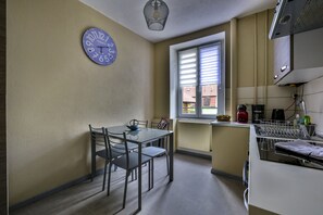 Eine Küche mit Esstisch, Stühlen, einer Uhr, einem Fenster und Küchengeräten.