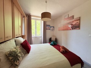 Un dormitorio con cama, armario, ventana y una obra de arte en la pared.