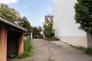 Un callejón estrecho con un edificio a la izquierda y un rascacielos al fondo.