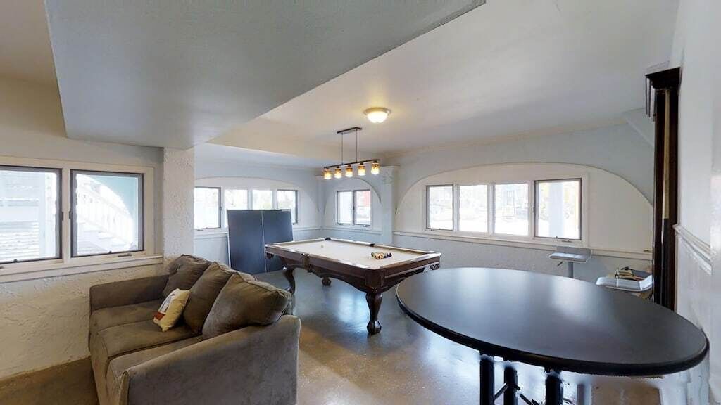 A room with a pool table, a sofa, and a dining table.
