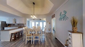 A spacious kitchen with a central island, white cabinetry, and a dining area with chairs. - LARGE,Pool,pool table,Arcade,2 Golf Carts,6 Kayaks,free linen,Hot Tub,near beach (Murrells Inlet)