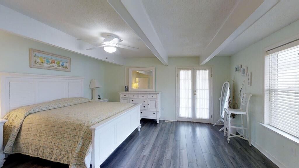 A bedroom with a bed, dresser, vanity, and a ceiling fan.