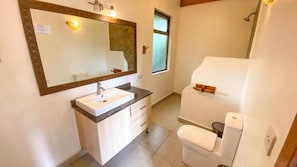 A bathroom with a white sink, mirror, and toilet. - Stay.Plus Nakuru Luxury Villas (Njoro)