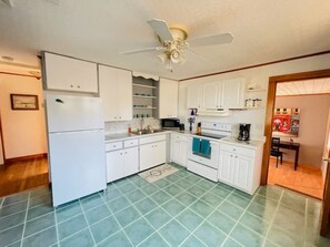Compact kitchen with a sink, stove, and microwave, featuring a small island and a door to a dining area.