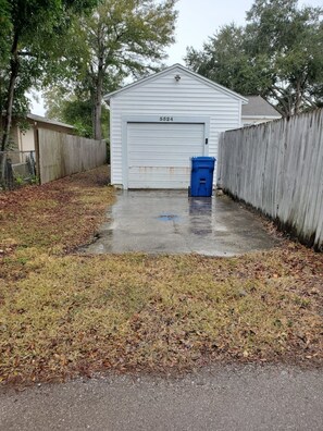 Situated in a yard, this garage features a white exterior and a numbered door.