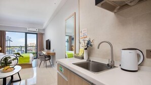 Una habitación de hotel moderna con cocina, una mesa de comedor y vistas a la ciudad.