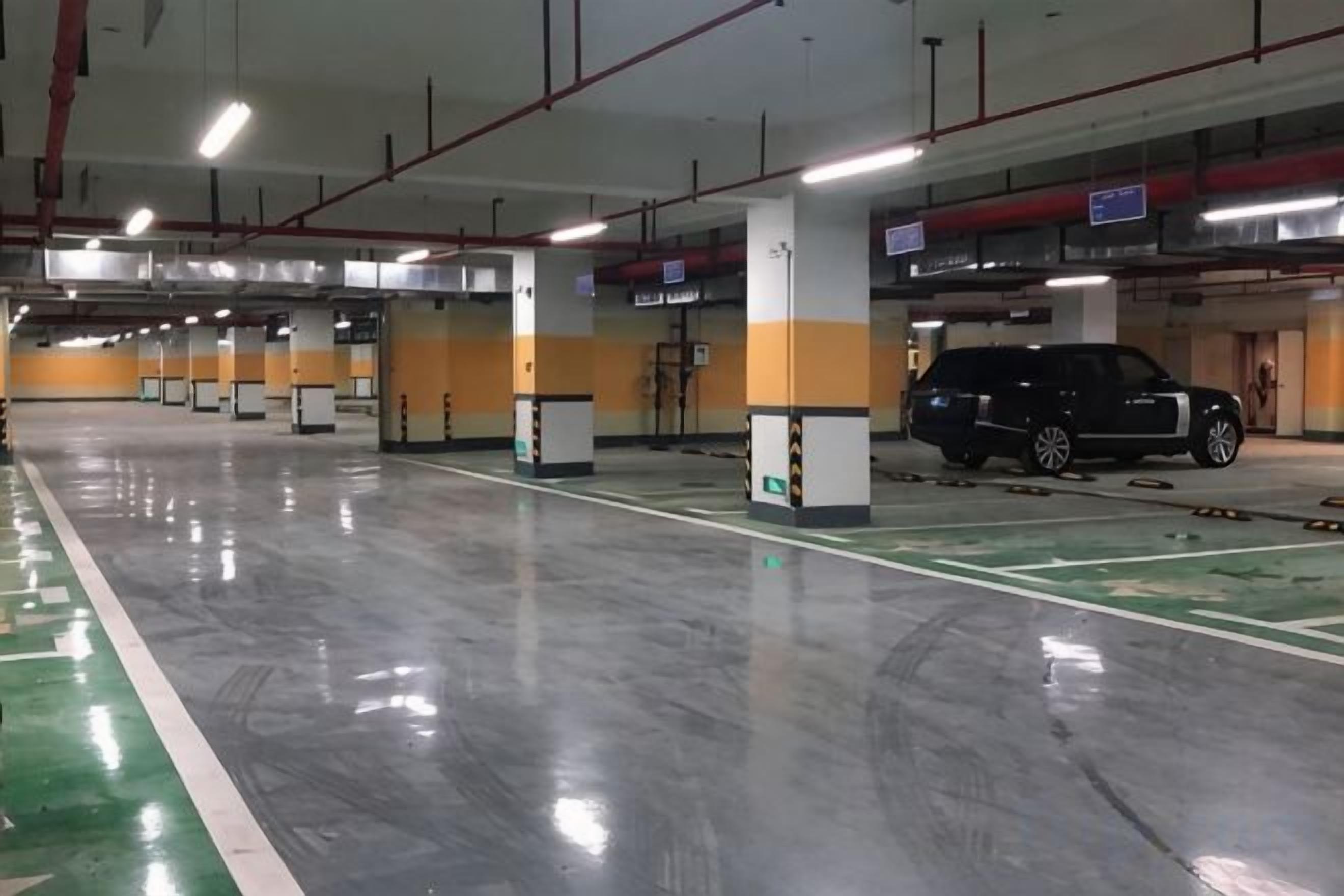 Un aparcamiento de varios niveles con señalización clara, suelo limpio y un vehículo estacionado en una de las plazas.