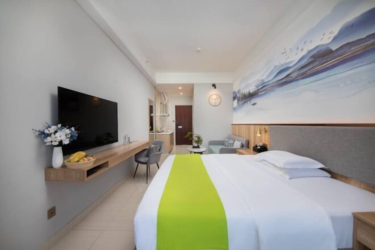 Habitació d'hotel amb un llit, una televisió, un escriptori i un quadre a la paret.