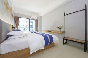 A modern hotel room with a large bed, a wooden bench, a small shelf with a vase, and a city view through the window. - Light Time Hotel (Nanning Greenland Central Plaza) (Nanning)